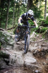 Auf wurzeligem Untergrund fährt eine Person mit dem Mountainbike bergab