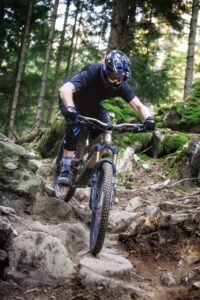 Auf wurzeligem Untergrund fährt eine Person mit dem Mountainbike bergab