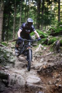 Auf wurzeligem Untergrund fährt eine Person mit dem Mountainbike bergab