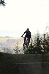 Eine Person am Mountainbike springt über einen Kicker