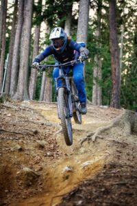 Eine Mountainbikerin fährt über wurzeligen Untergrund