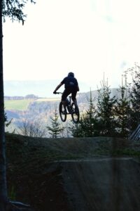 Eine Person am Mountainbike springt über einen Kicker