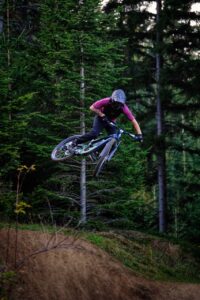 Eine Person am Mountainbike springt über einen Kicker