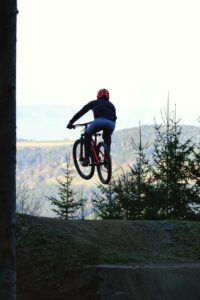 Eine Person am Mountainbike springt über einen Kicker