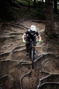 Ein Mountainbiker fährt im Wald über Wurzeln auf der Downhill Strecke der Wexl Trails